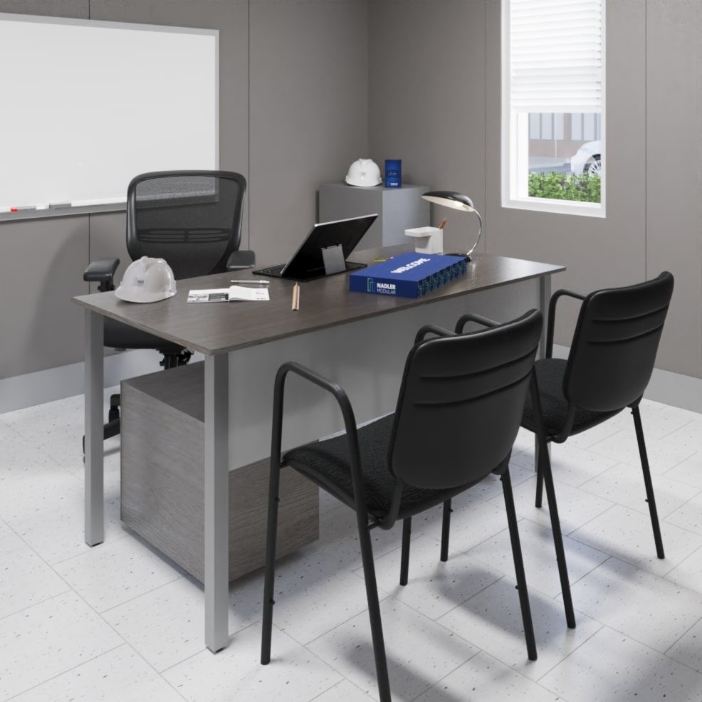 A modern office scene featuring a desk with a laptop, a hard hat, pens, papers, a binder, and an adjustable desk lamp. Behind the desk is an office chair, with two guest chairs in front. A whiteboard is mounted on the gray wall, and a window allows natural light in.
